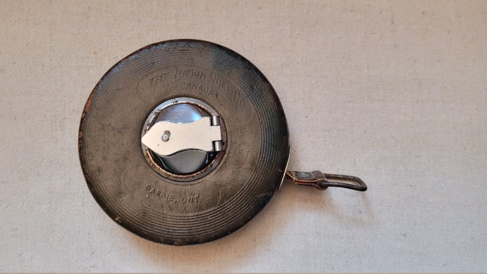Vintage Lufkin Rule Co Canada tape measure with wind chrome hand crank and brown stitched leather, manufactured in Barrie, Ontario