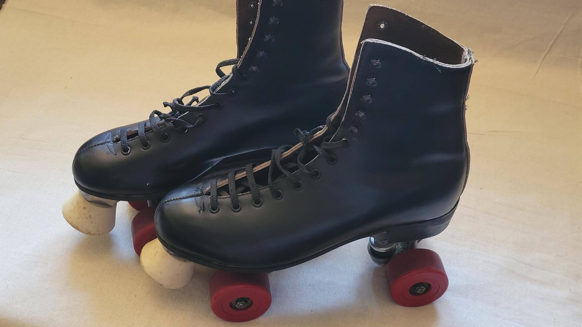 Beautiful vintage Dominion Marathon classic black leather roller skates with red wheels, white rubber brakes, and cast aluminum frame. This retro antique made in Canada collectible sports equipment and rollerskating memorabilia
