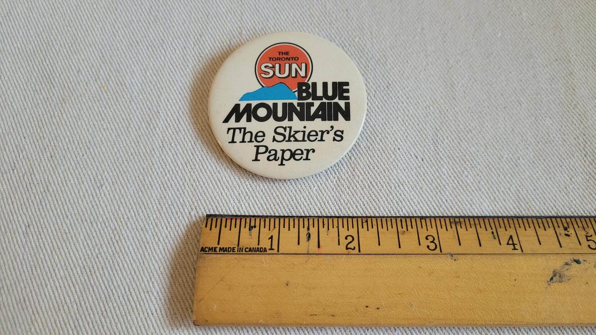 Rare vintage Toronto Sun Newspaper "The Skier's Paper" pinback button. Retro collectible badge celebrating Blue Mountian, Ontario's largest snow and four season resorts near Collingwood ON