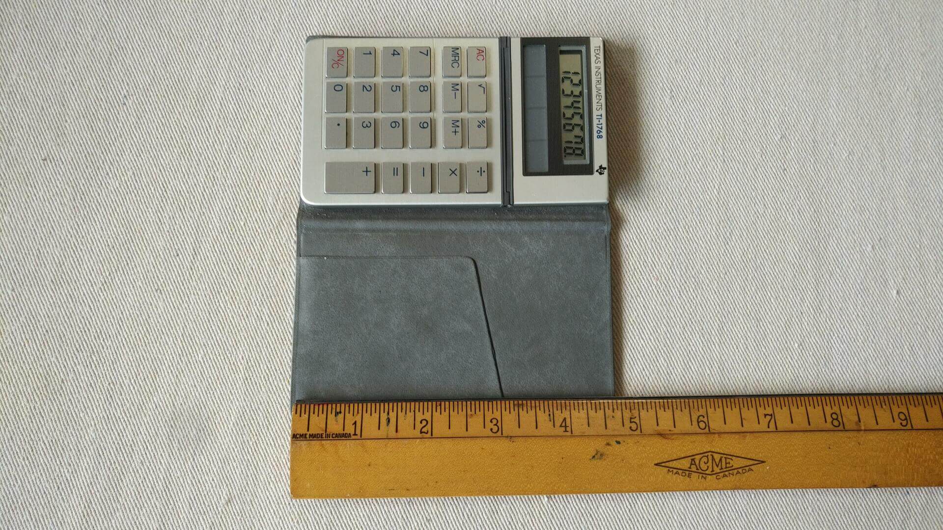 1980s Texas Instruments model TI-1768 mini pocket solar calculator with tilt display and nice embossed grey TI sleeve. Vintage collectible office equipment