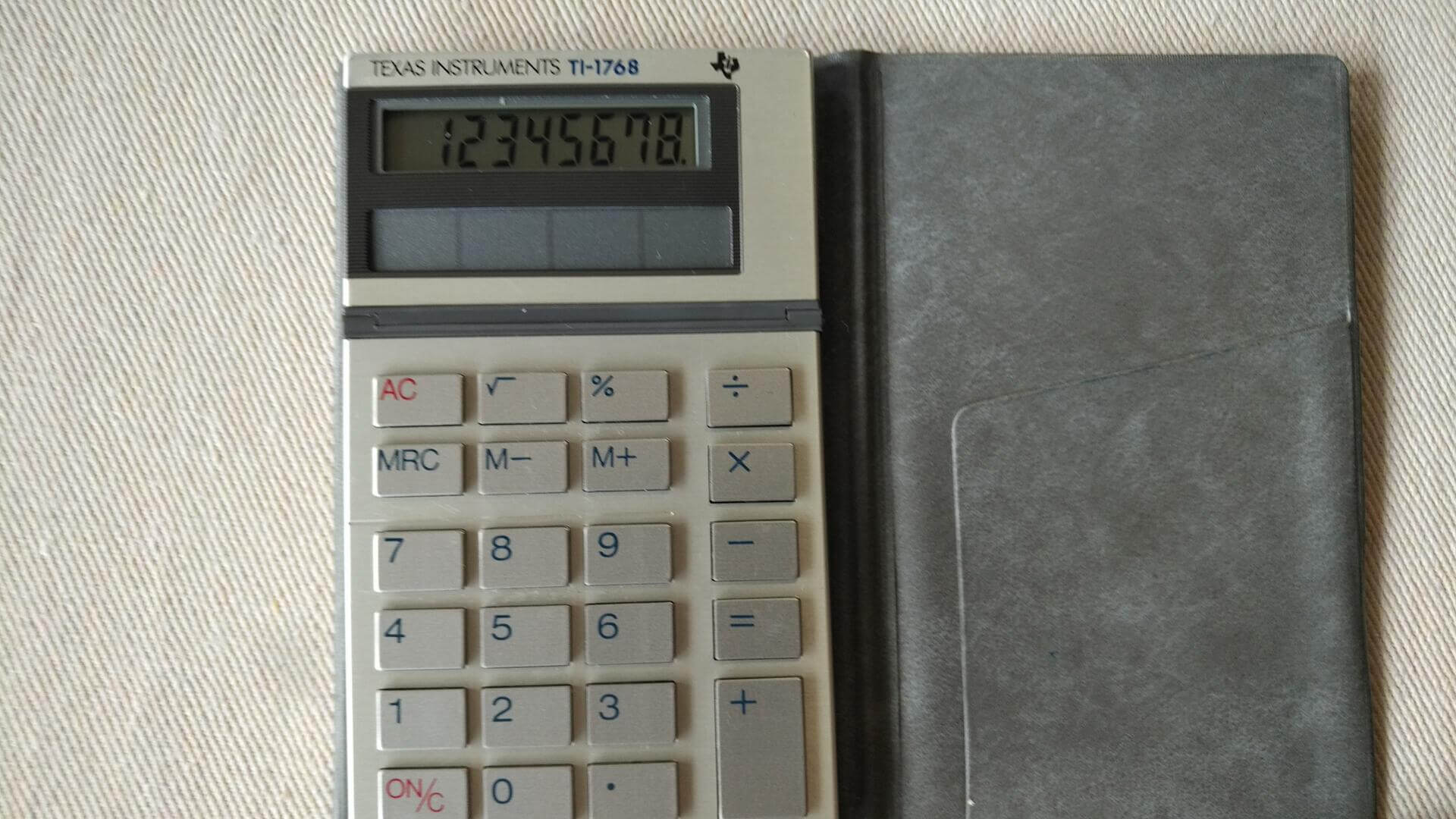 1980s Texas Instruments model TI-1768 mini pocket solar calculator with tilt display and nice embossed grey TI sleeve. Vintage collectible office equipment