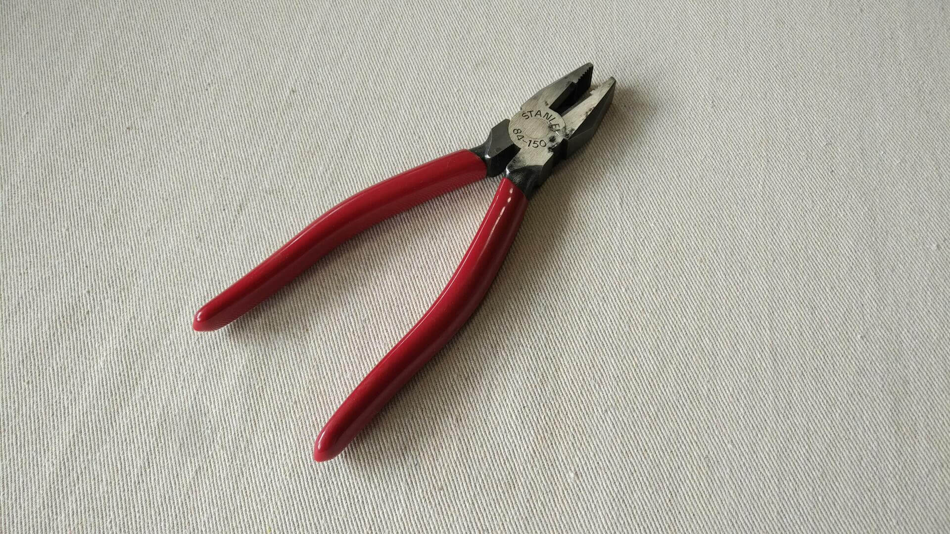 Nice pair of Stanley 84-150 lineman's combination pliers cutters with red insulated handles 7 1/2 inches long. Vintage made in Japan collectible electrician gripping and cutting hand tools